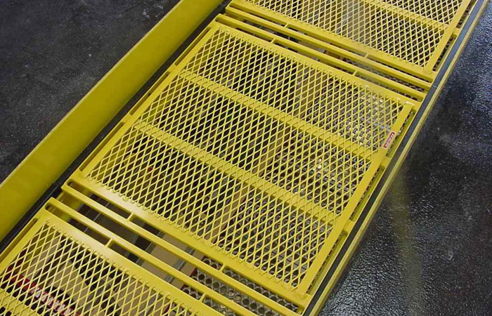 EZ Glide yellow grated pit safety cover installed over a quick lube bay to prevent accidents and ensure OSHA compliance
